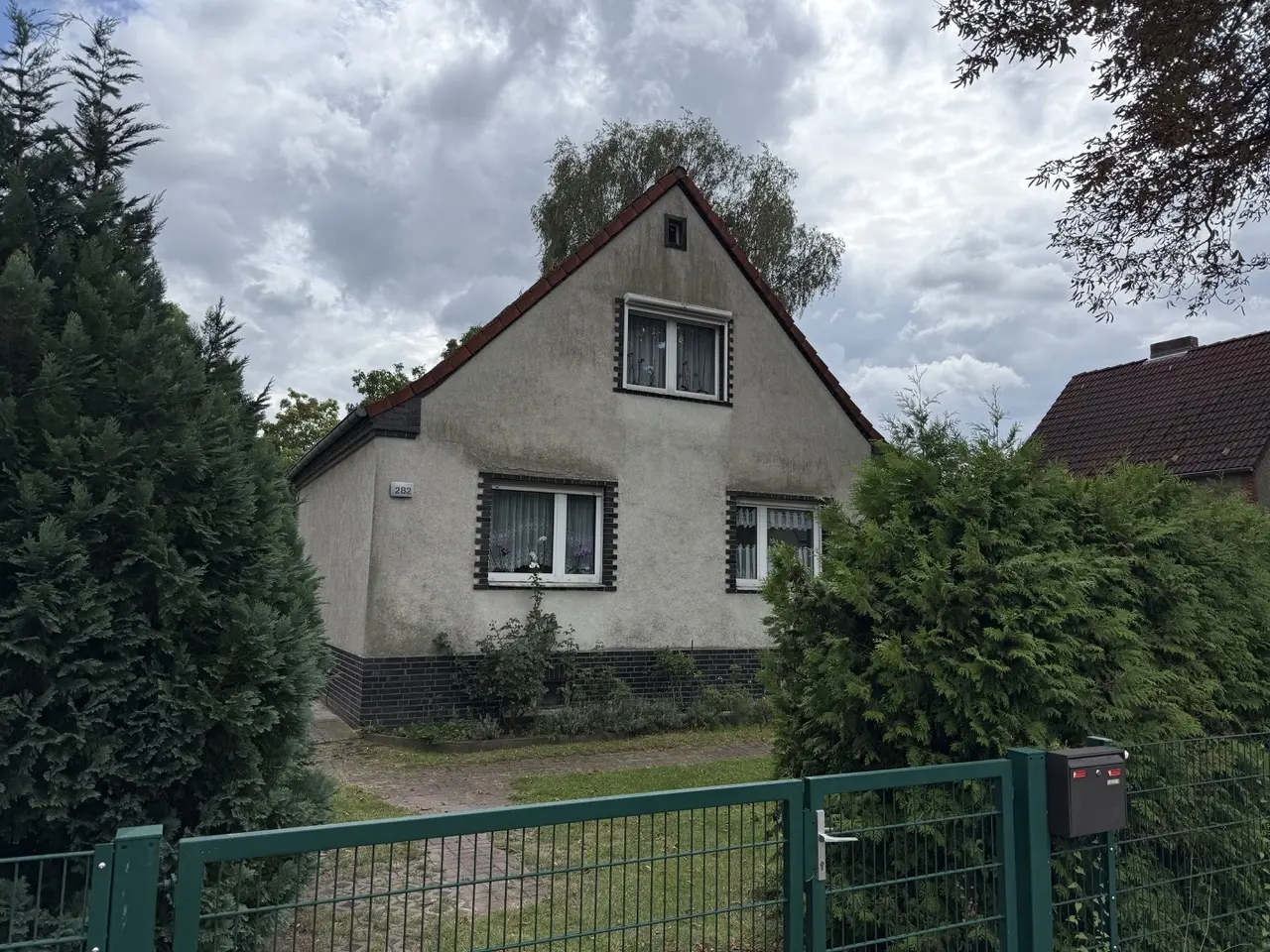 Wohnhaus Hönower Straße 282 in Mahlsdorf mit steilem Satteldach, Putzfassade und dunklen Klinkereinfassungen an Fenstern und Sockel
